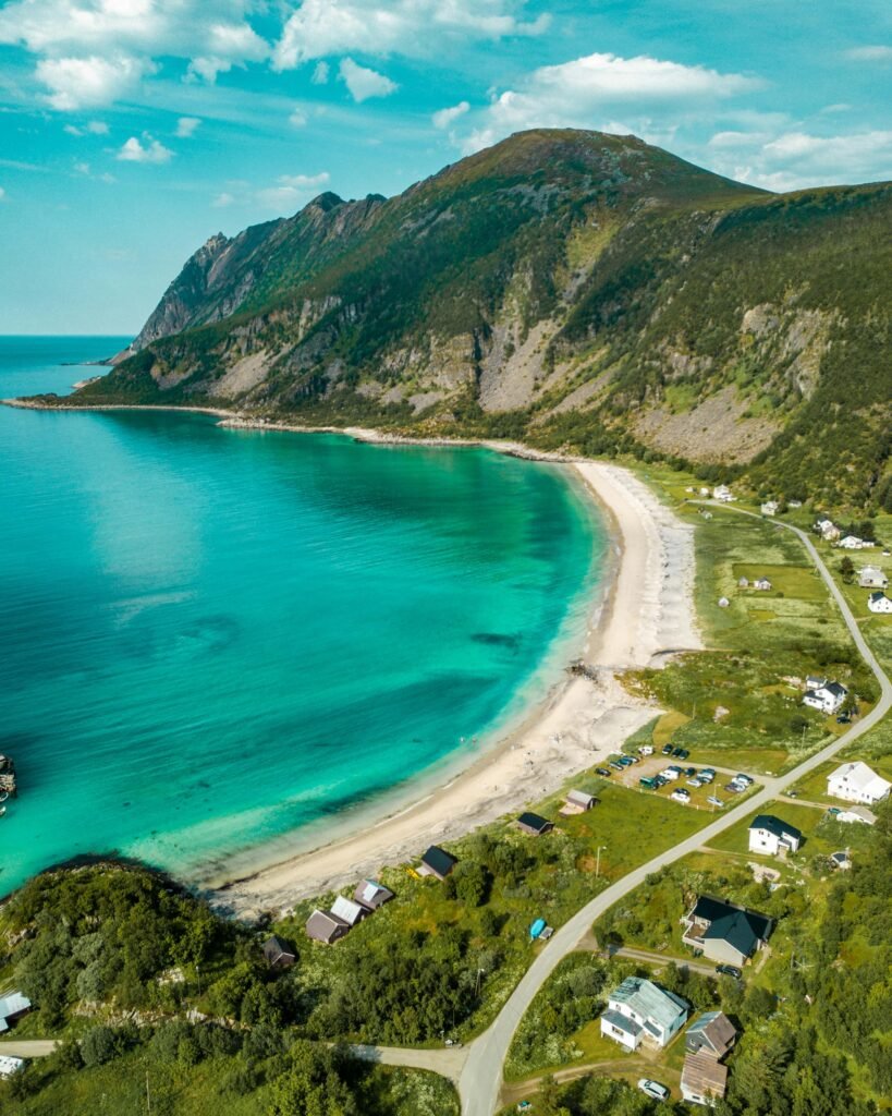 Scenic aerial view of a tranquil bay surrounded by lush mountains and beach houses.