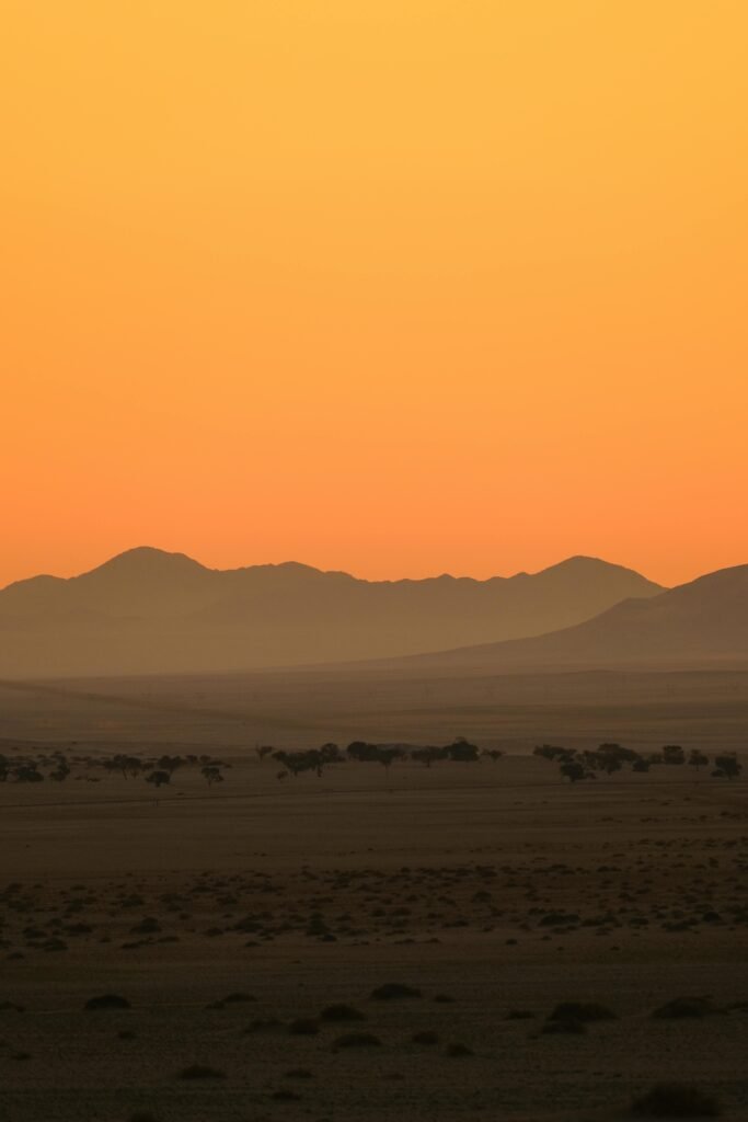 A serene desert scene with mountains silhouetted against a golden sunset sky.