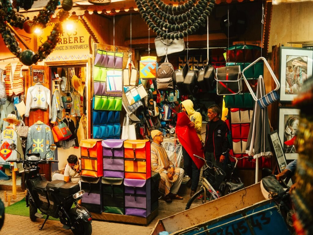 Colorful market stall in Marrakech medina displaying textiles and crafts, capturing vibrant local culture.