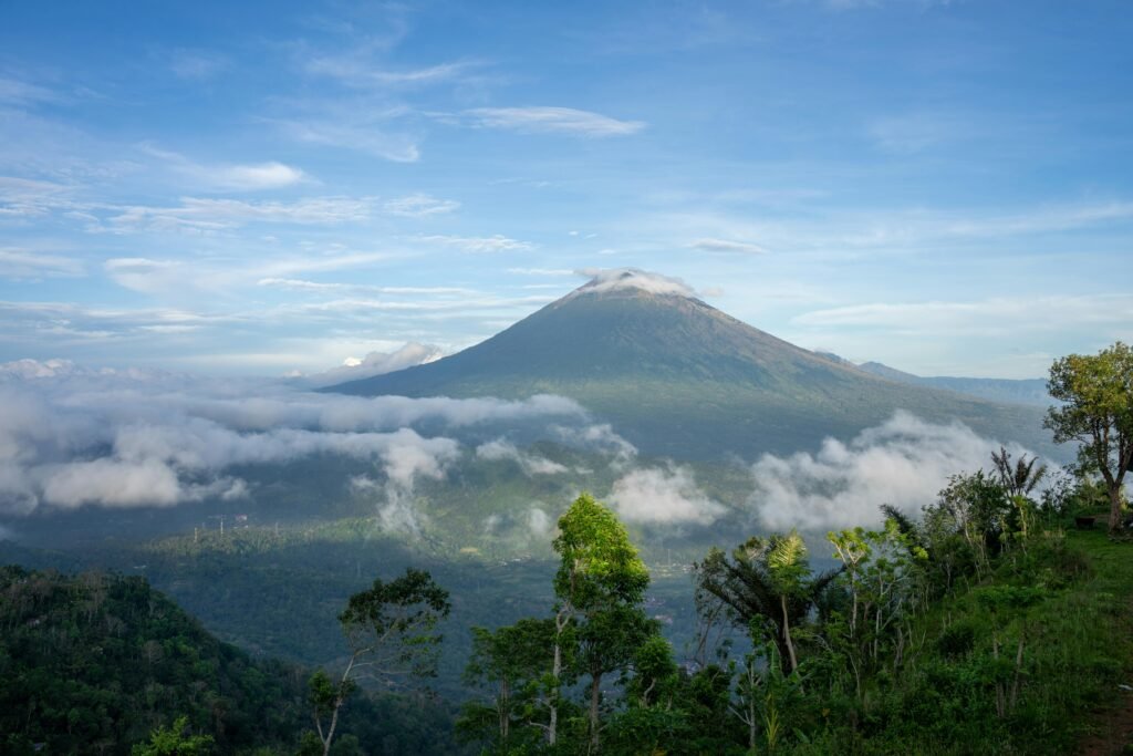 Breathtaking landscape of Mount Agung surrounded by clouds and lush greenery in Bali, Indonesia.