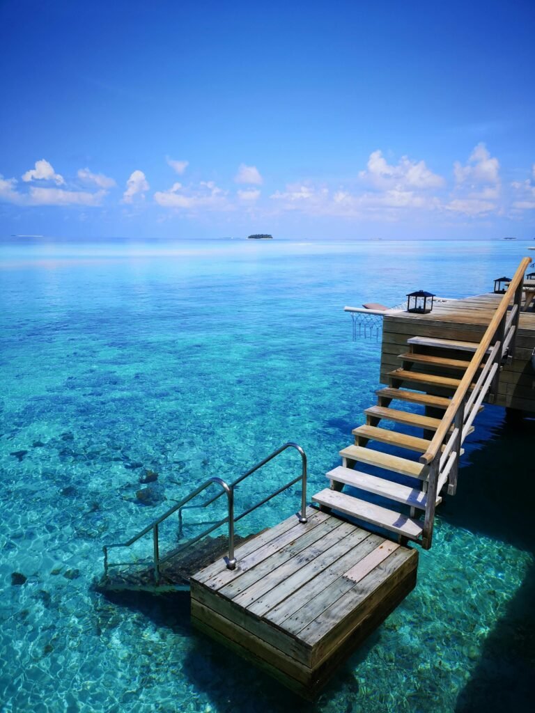 Top 10 des plus belles îles paradisiaques 🌴 Wooden stairway leading to azure waters in tropical Maldives paradise.